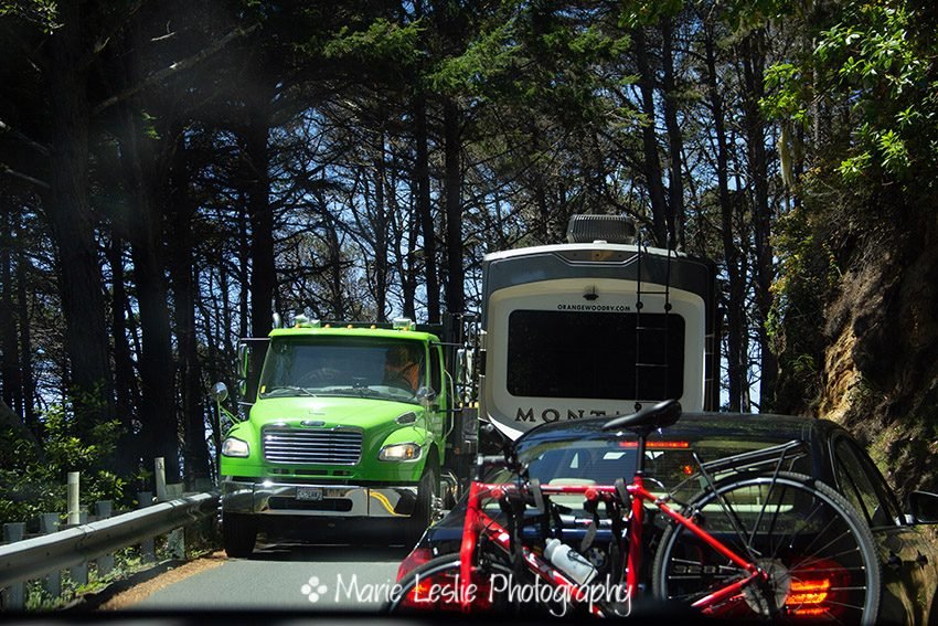 vehicles passing on a a narrow curving stretch of Highway 1. The Pacific Coast Highway